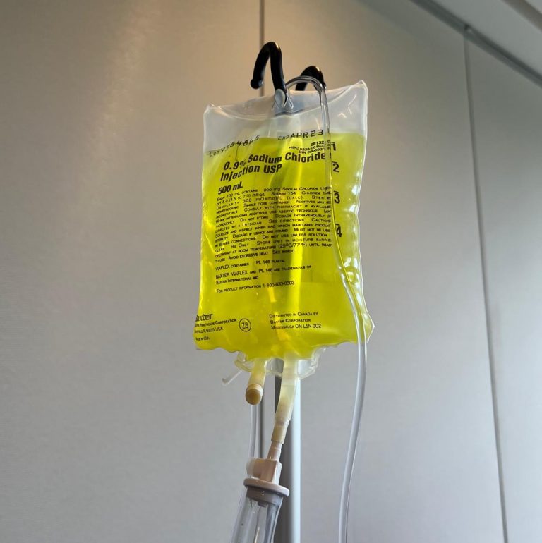 An IV with a label and text that reads "0.9% Sodium Chloride Injection USP".